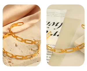 Close-up of golden chain link bangle with 18K gold plating on textured stone