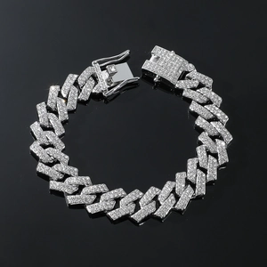 Detail of silver iced out Cuban link bracelet with clear rhinestones on a black background