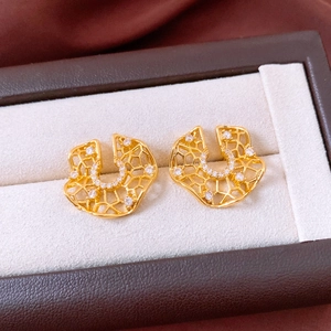 Detail of vintage hollow round earrings with gold finish and inlaid white zircon stones