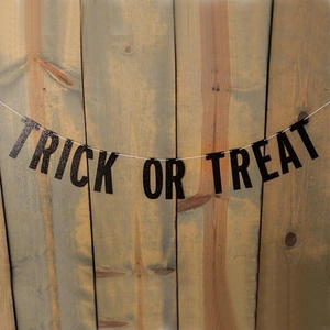 Glittering black Trick or Treat banner hanging on rustic wood wall for Halloween decor