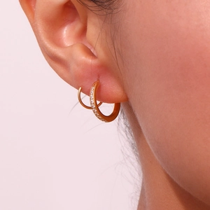 Détail de boucles d'oreilles spirales en or 18K avec diamants portées à l'oreille