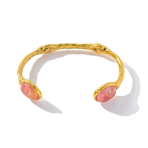 Detailed close-up of a gold-plated textured open cuff bracelet with pink oval gemstones