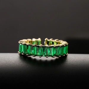 Golden open ring featuring emerald cut green cubic zirconia on a minimalist display stand