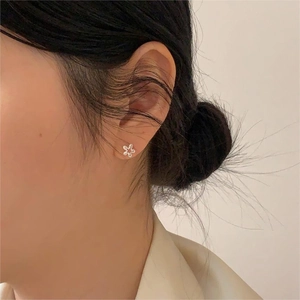 Close-up of minimalist 925 sterling silver flower stud earrings on a model's ear
