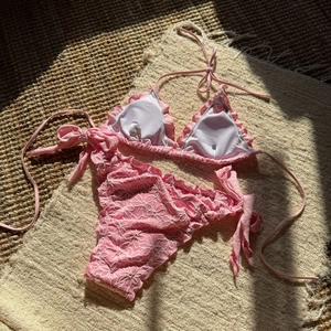 Detail of pink floral embroidery and ruffled edges on a two-piece triangle bikini set