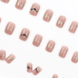 Short round press-on nails in nude pink with black abstract patterns and gold foil flakes