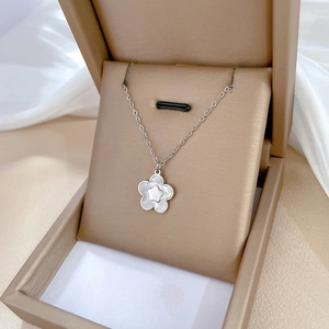 Macro shot of silver titanium steel flower necklace with shell inlay in a beige jewelry box