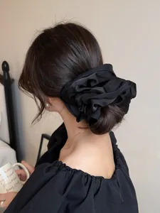 Close-up of elegant black oversized satin scrunchie on a woman's low bun hairstyle