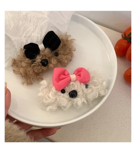 Close-up of cute plush puppy hair clips with bows on a white plate in hand
