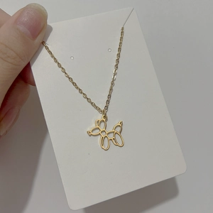 Détail d'un collier avec pendentif chien ballon doré sur une carte d'affichage blanche