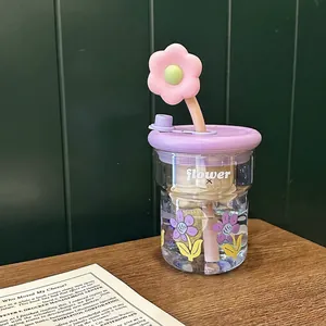 Détail d'une tasse en verre floral avec paille fleurie mauve et couvercle étanche