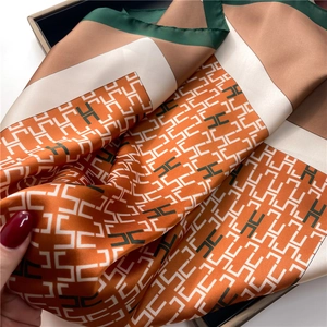 Pañuelo de seda de lujo con patrón de letra H naranja en una caja de regalo premium