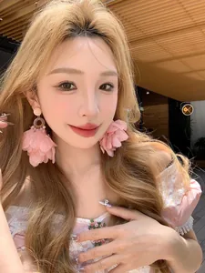 Boucles d'oreilles pendantes en tissu rose portées par un mannequin en extérieur