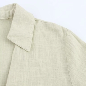 Detail of light beige linen shirt dress showing collar stitching and fabric texture