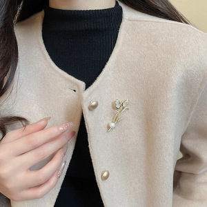 Detail of 14K gold plated tulip brooch with sparkling zircons and a white pearl on a coat