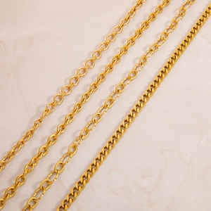Macro detail of four assorted 18K gold plated stainless steel chain styles on marble
