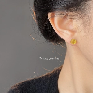 Macro shot of a yellow resin rose stud earring worn on a model, elegant floral detail