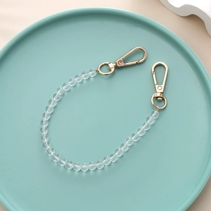 Close-up of a clear beaded strap with gold lobster clasps in a decorative tray