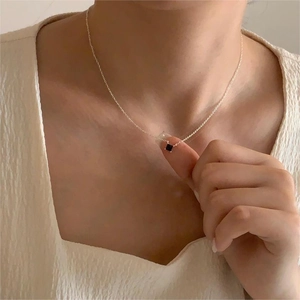 Close-up of minimalist silver necklace featuring a square black zircon pendant in 4-prong setting