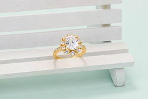 Golden sunflower halo ring with a central oval white gemstone on a wooden bench model