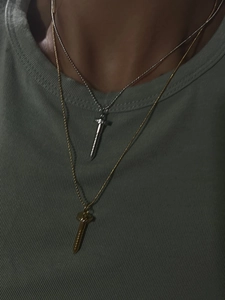 Close-up of gold and silver screw-shaped pendants on fine chains worn by a model