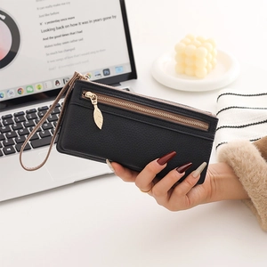 Detail of black pebbled leather long wallet with golden leaf zipper pull and hand strap