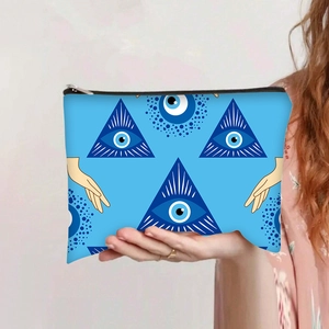 Detail of blue makeup bag with evil eye print held by hand in a home setting