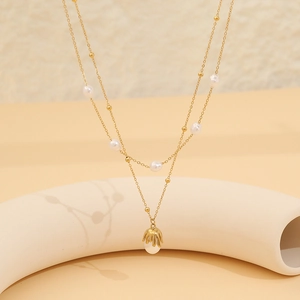 Detail of gold double-layer necklace with white pearls and lava-style molten pendant