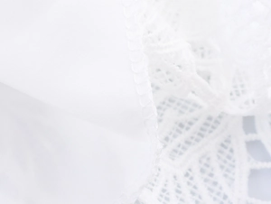 Close-up of white lace stitching and plain woven fabric details on a two-piece dress set