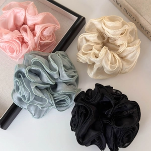 Macro shot of assorted sheer floral scrunchies with delicate ruffled edges in four colors
