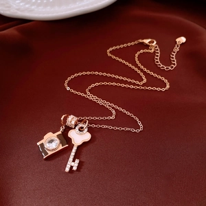 Macro shot of rose gold key and camera charms with zircon on red satin background
