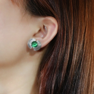 Macro shot of green cat eye fan-shaped stud earrings on ear with silver textured metal