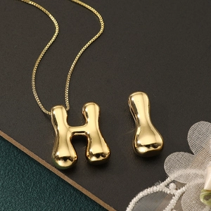 Macro view of gold initial letter H and I pendants with sleek metallic texture and fine chain