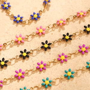 Minimalist daisy chain bracelet with colorful enamel flower charms on a gold-plated link chain