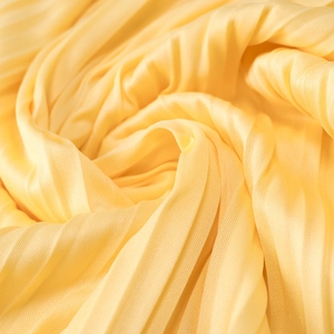 Gros plan sur le tissu plissé jaune avec texture en maille fine et plis élégants