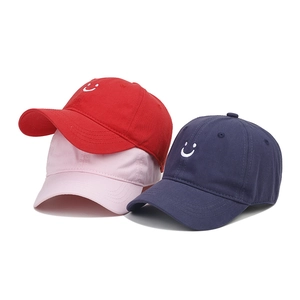 Detail of embroidered smile pattern on colorful cotton baseball caps for kids