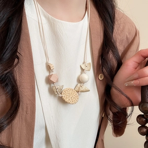 Detail of bohemian rattan round pendant necklace with geometric wood beads on model