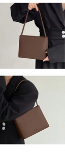 Brown leather square handbag shown held by a model in a black suit for professional style