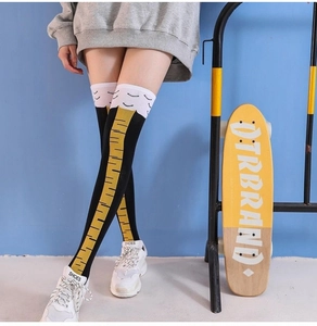 Detailed view of creative chicken leg over-knee socks worn by a model in a street style setting