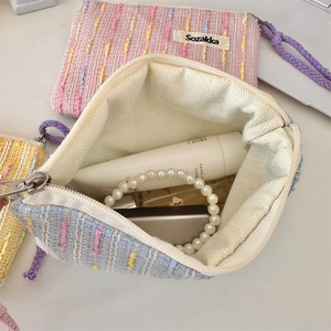 Detailed view of woven tweed makeup pouches with zipper and colorful stitch texture