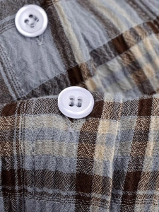 Makroaufnahme von kariertem Baumwollstoff mit weißen Knöpfen am beigen Kleid
