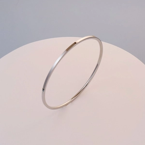Polished silver minimalist stainless steel bangle shown on a pink pedestal