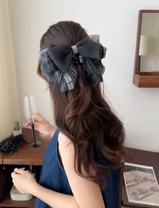 Detail of elegant black chiffon bow hair claw clip with silver rhinestones on a woman