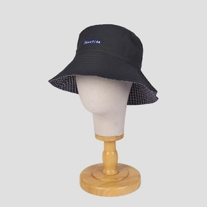 Classic black bucket hat with plaid lining and blue brand label on a display stand