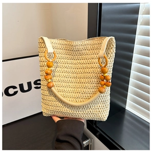Detail of hand-held beige straw bucket bag with hollow weave and wooden bead handle
