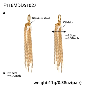Detailed view of long tassel earrings with white oil drip letter K and gold finish