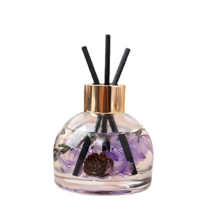 Preserved flower car scent diffuser with purple flowers and pine cones in a glass bottle