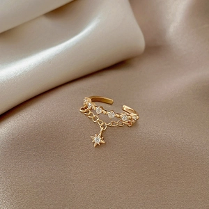 Golden geometric chain ring with star pendant and small crystals on beige satin fabric