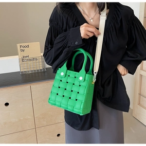 Chic green woven EVA square beach bag with white strap worn by a model in casual setting