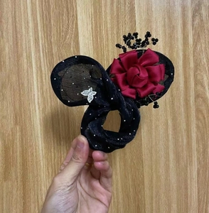 Detail of mesh hair scrunchie with silver dots, butterfly charm, and red fabric rose